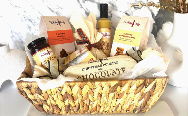 Gift basket with Christmas pudding, chocolate, and other items on a marble surface