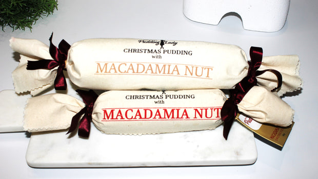 Two sizes of macadamia nut traditional pudding log wrapped in calico on a marble board