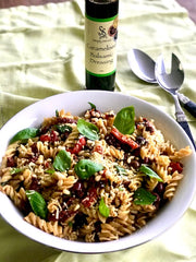 Warm pasta salad with bottle of Simply Stirred Caramelised Balsamic Dressing plated looking deliciious