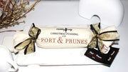Port & Prunes pudding log decorated with calico and ribbon on a marble plate