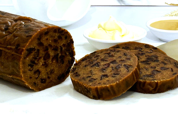 Whisky & marmalade pudding log plated on white plate, sliced