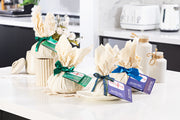 Selection of gluten free puddings wrapped in calico on a kitchen counter with labels