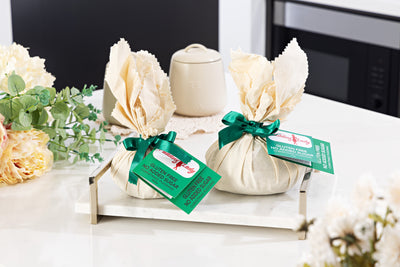 Two gluten free with no added sugar, round puddings wrapped in calico on a marble serving tray