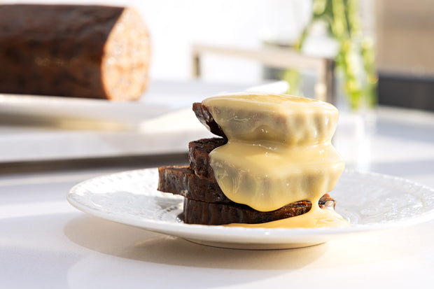 Traditional pudding log sliced with  brandy custard sauce on a white plate