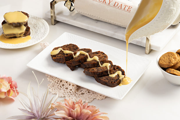 Sticky date pudding log sliced and plated on white plate with beautiful table setting 