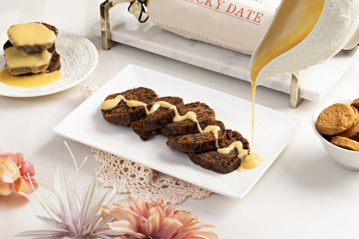 Sticky date pudding log sliced and plated on white plate with beautiful table setting 