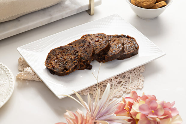Chocolate and macadamia log pudding sliced on white plate with pretty table setting 