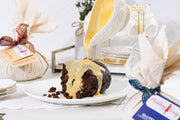 Gluten free pudding with custard being poured over it on a table setting.