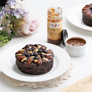 Pudding Lady Chocolate Fruit cake plated and  pictured with a jar of decadent chocolate sauce