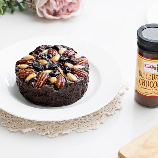 Pudding Lady Chocolate Fruit cake plated and pictured with a jar of decadent chocolate sauce