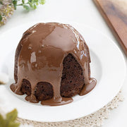 Deliciously decadent chocolate sponge pudding on a white plate with chocolate sauce dripping